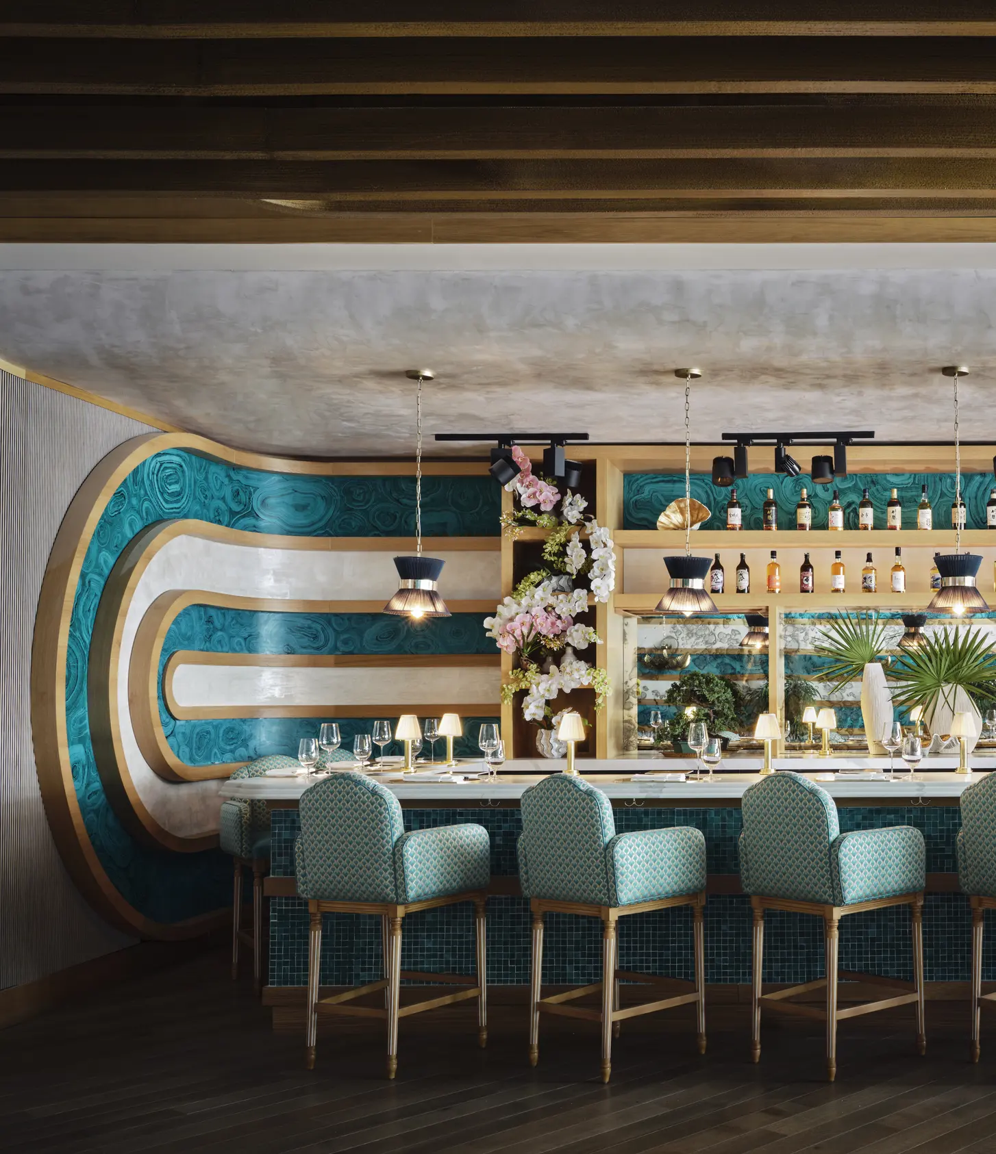 A teal bar counter lined with stools
