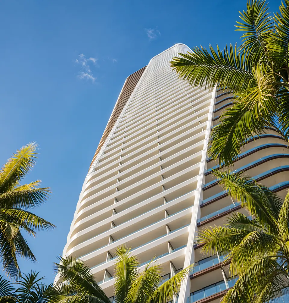 The tower rising behind palms, seen from below